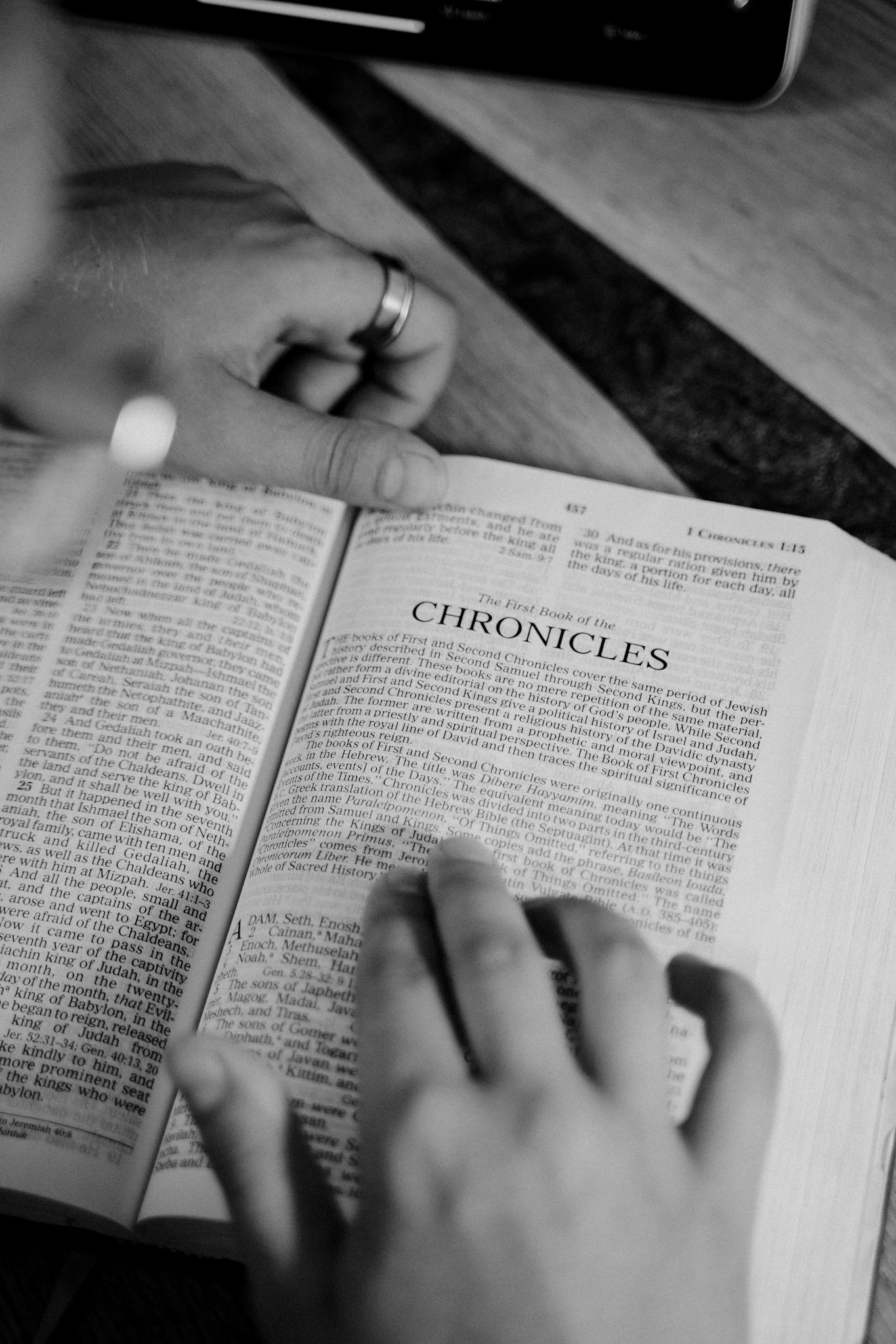 Grayscale Photo of a Person Reading a Bible